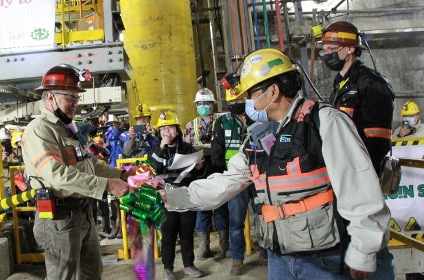 Mark Johnson, Director, Executive Vice President and Chief Operating Officer-PTFI (left), celebrates the successful startup of Crusher 602 with employees at Grasberg Block Cave. 